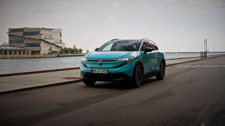 Nissan LEAF bleu AOBA qui roule de ¾ avant à proximité d’un port dans le nord de l’Europe