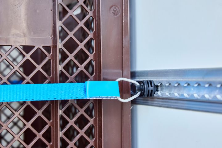 Detailaufnahme eines blauen Verzurrgurtes im Nissan Interstar-e mit Bäckereikoffer, der einen brauen Bäckereikorb hält