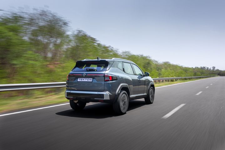 Rear three-quarter view of the Nissan Tekton driving along a straight road.
