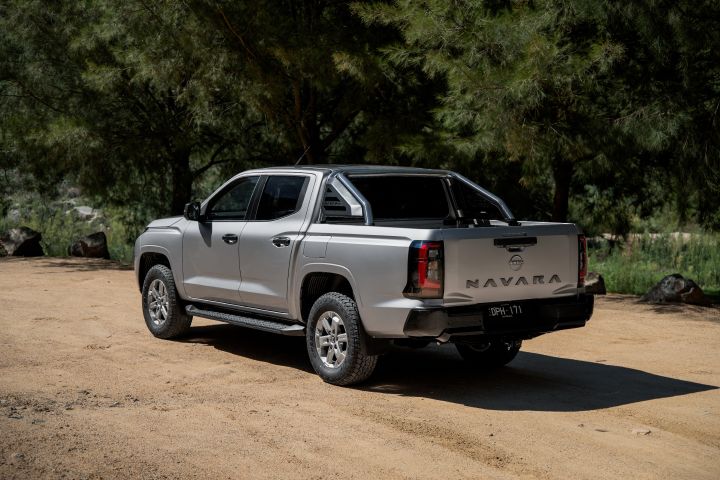 2026 Nissan Navara ST dual cab ute finished in Summit Silver photographed from the rear-left angle, featuring the tray sports bar, alloy wheels and NAVARA tailgate.