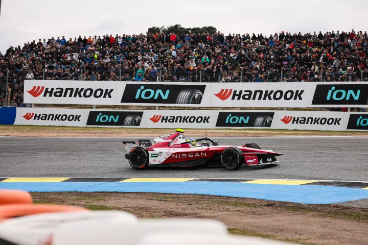 Seitenaufnahme von Oliver Rowland auf der Rennstrecke im Auto mit der Startnummer 1, hinter ihm Hankook-Werbetafeln und Fans auf den Tribünen.