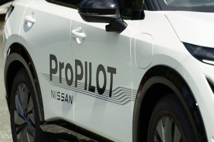 Nahaufnahme der Seite eines weißen Nissan Ariya mit der schwarzen Aufschrift ProPILOT Nissan