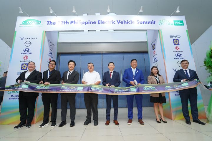 A group of people standing during the ribbon cutting of this year Electric Vehicle Summit