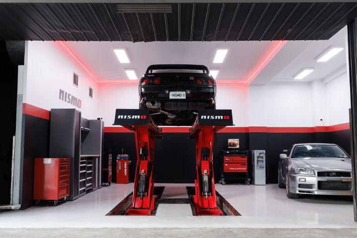 A black R32 GT‑R on a hoist within the workshop of the new NISMO Performance Center Melbourne.