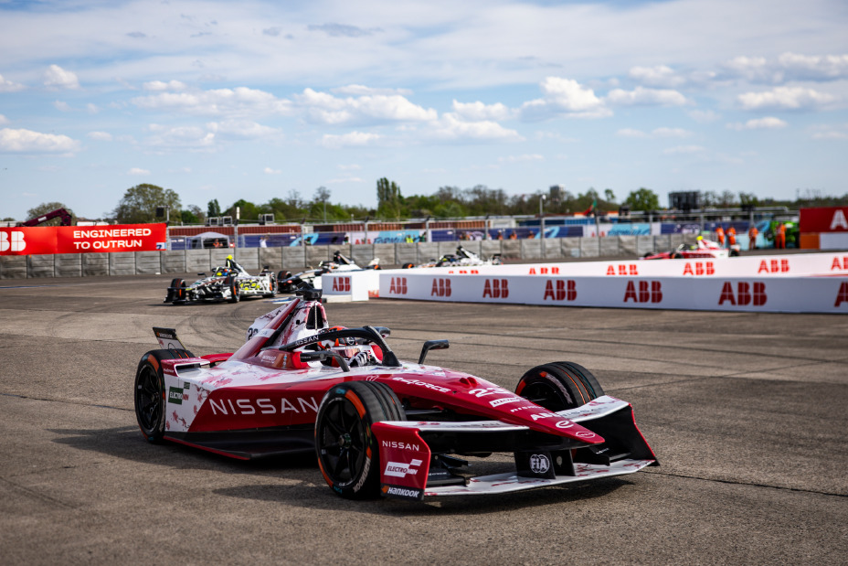 Front/side shot of Norman Nato driving the #23 Nissan e‑4ORCE 05 during the Berlin E-Prix with white ABB advertising boards also visible in the image.
