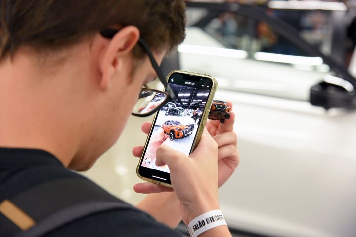 Homem fotografa minuatura com um celular