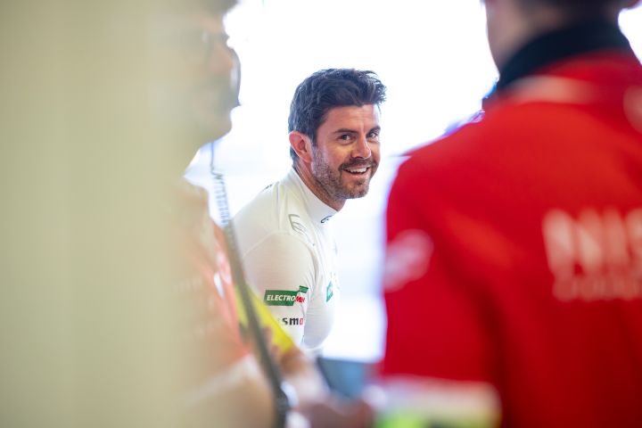 Norman Nato lächelt in der Garage des Nissan Formula E Teams mit seinem weißen Unterhemd.