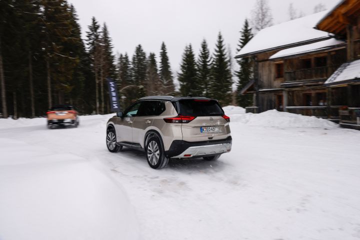 Heckansicht eines fahrenden, silbernen Nissan X‑Trail e‑Power e‑4ORCE im Schnee