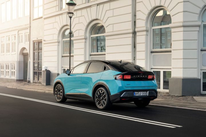 3/4 Heckansicht eines türkisen Nissan LEAF, der am Straßenrand vor einem klassischen Gebäuden mit weißer Front parkt