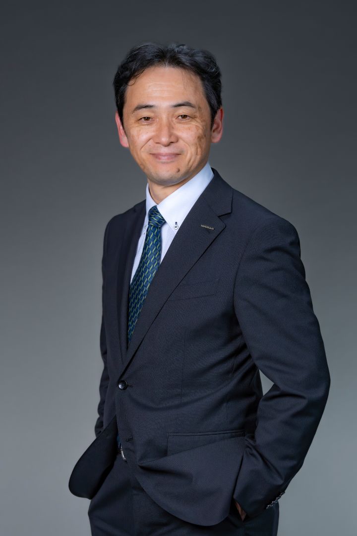 Portrait of Eiichi Akashi (suit, tie and NISSAN corporate pin) (smailing and hands in suit pockets)