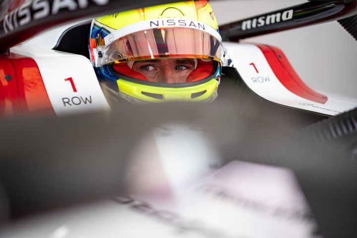 Oliver Rowland mit aufgesetztem Helm und hochgeklapptem Visier sitzt im Auto mit der Nummer 1 in der Teamgarage.