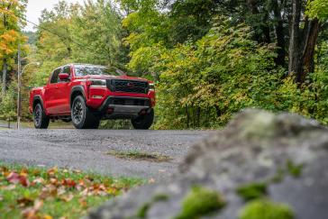 Prise de vue avant droite d'une Nissan Frontier rouge roulant du côté gauche de l'image vers la droite