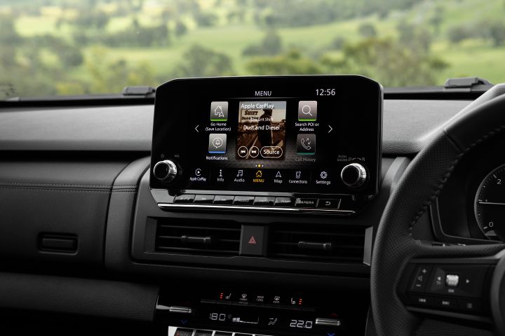 Centre dashboard view of a 2026 Nissan Navara ST-X showing the 9-inch Touch infotainment screen open to a menu with Apple CarPlay and audio source tiles, with central air vents and climate controls below.