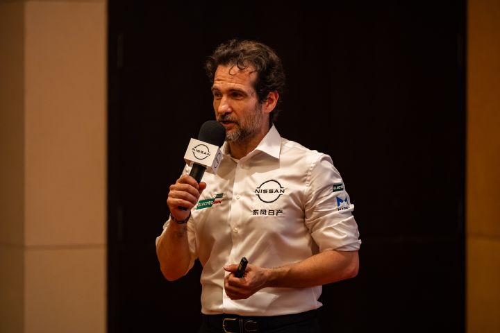 Tommaso Volpe trägt sein weißes Teamshirt und hält ein Mikrofon in der rechten Hand.