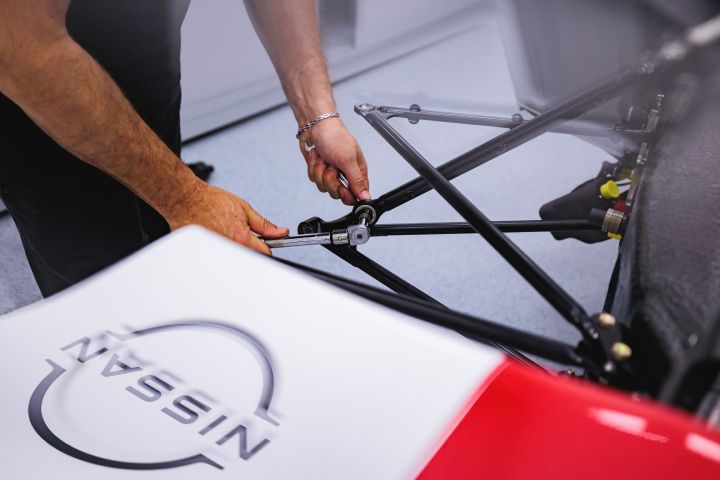 Nahaufnahme eines Mechanikers, der Schrauben am Nissan Formel E Rennwagen einstellt