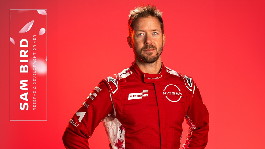 Sam Bird a posar para a câmara com as mãos na cintura e vestido com a roupa vermelha da equipa.