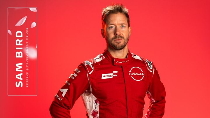 Sam Bird a posar para a câmara com as mãos na cintura e vestido com a roupa vermelha da equipa.