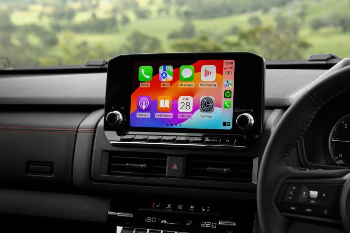 2026 Nissan Navara PRO-4X finished in Boulder Grey showing the centre touchscreen with Apple CarPlay icons above the air vents and climate panel.