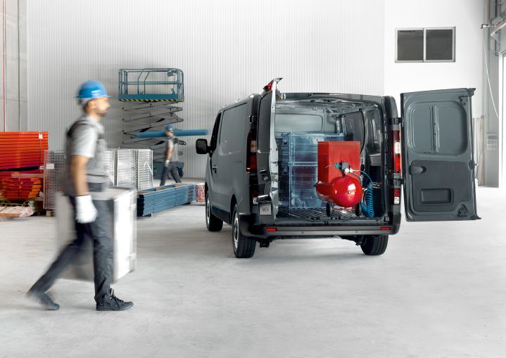 Nissan Primastar com portas traseiras abertas e com carga, com trabalhador a passar ao lado.