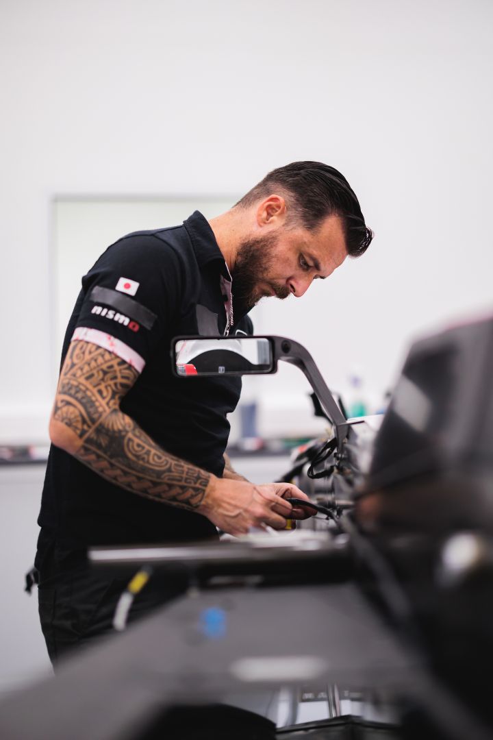 Ein Mechaniker montiert etwas am Nissan Formel E Rennboliden für die Saison 11