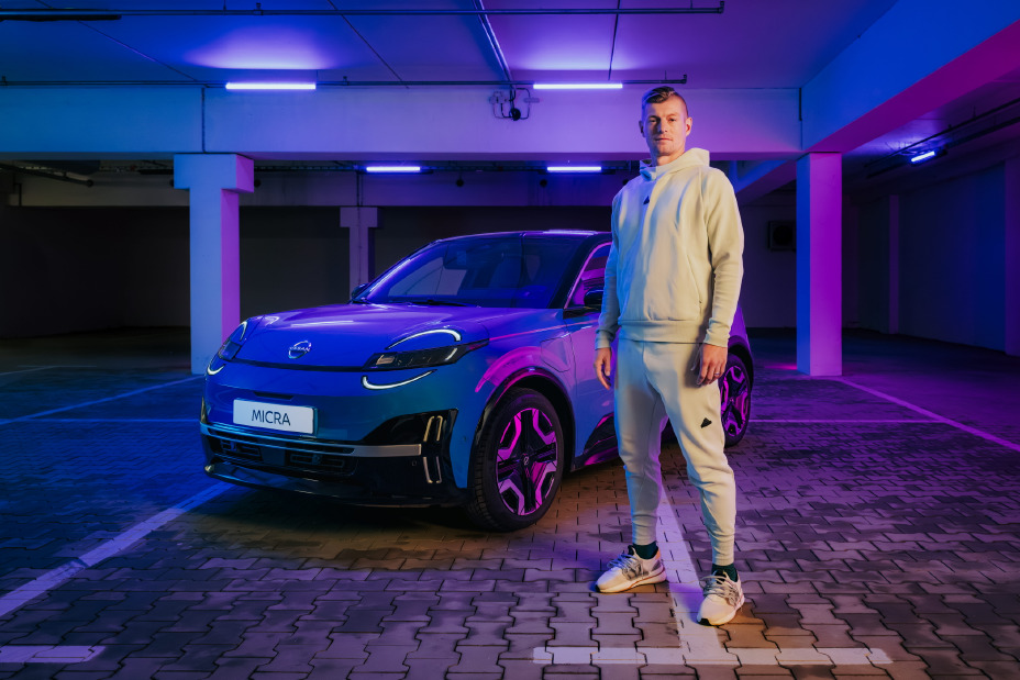 Toni Kroos steht in hellem Trainingsanzug neben einem blauen Nissan Micra