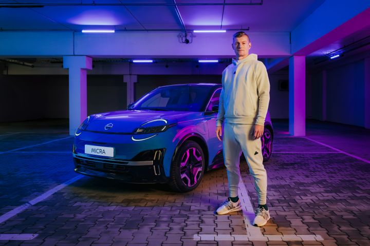 Toni Kroos steht in hellem Trainingsanzug neben einem blauen Nissan Micra