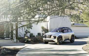 Un concepto Nissan Xmotion estacionado en la entrada de una casa contemporánea, parcialmente oscurecido por el follaje.