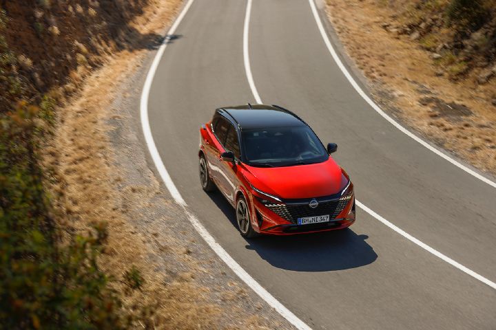 Vue ¾ avant plongeante sur un Qashqai e‑POWER rouge qui attaque un virage à gauche