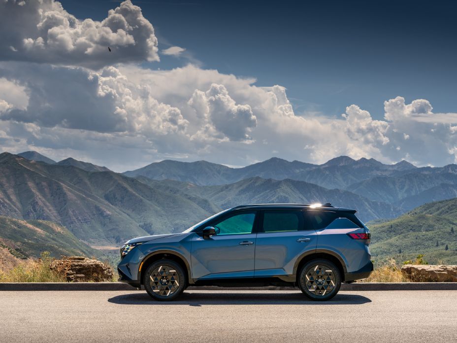 Left profile view of the 2027 Nissan Rogue Hybrid SR with mountains and clouds in the distance.