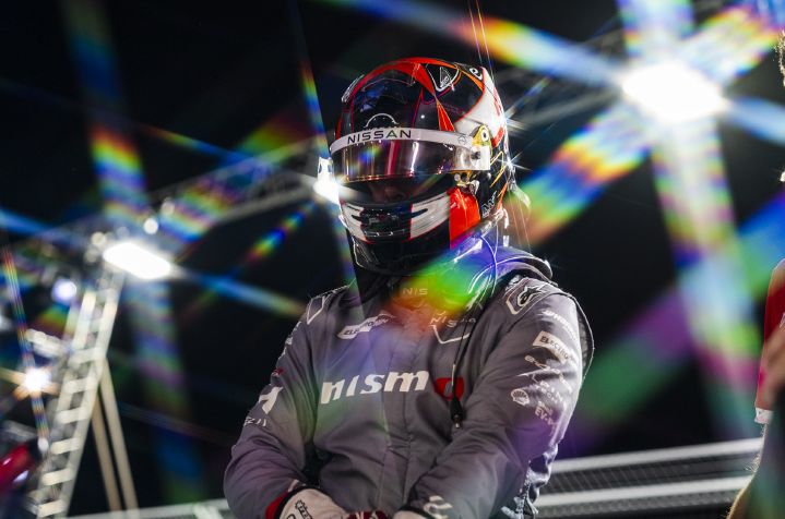Norman Nato steht mit aufgesetztem Helm und hochgeklapptem Visier vor dem E-Prix in Tokio im Scheinwerferlicht, gekleidet in seinen grauen Team-Rennanzug.