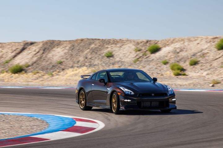 The Midnight Purple 2024 GT‑R T-spec Takumi curving around a track, arid landscaping sits along the edges of the track.