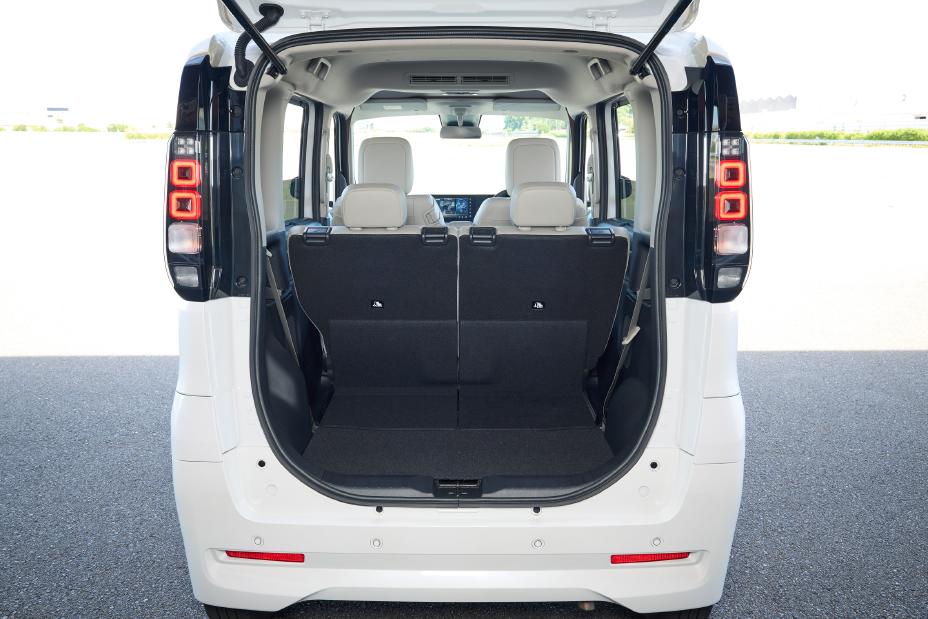 The rear of the new Nissan Roox kei car with its white body and back doors open. The interior shows the second-row seats, and the trunk space appears spacious with the seats in an upright position.