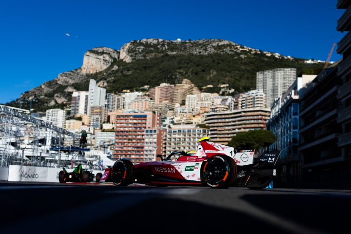Seitenansicht von Oliver Rowland am Steuer des Nissan Formel E Rennwagens mit der Startnummer 1 in Monaco, im Hintergrund ist das Fürstentum zu sehen.