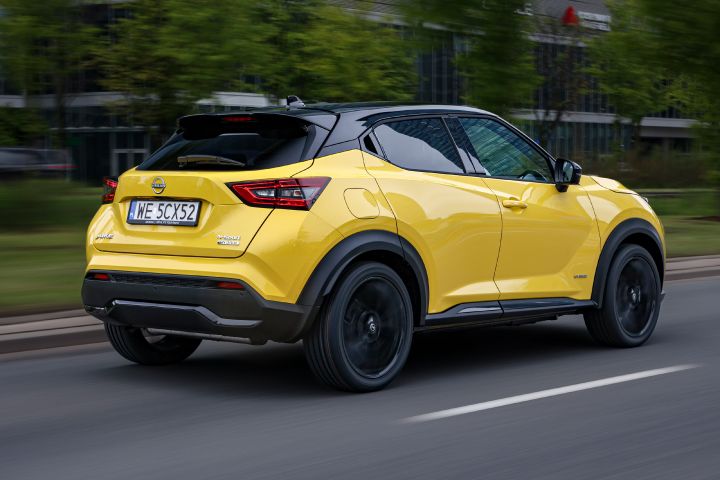 Jadący żółty Nissan Juke (widok z tyłu) z budynkami w tle