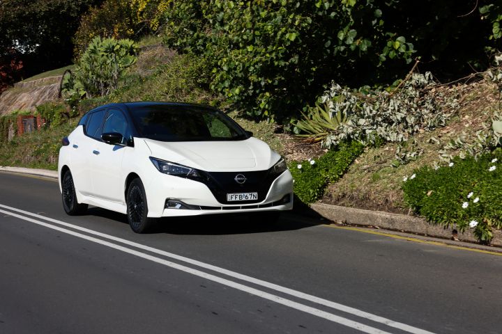 White Nissan Leaf driving down a road
