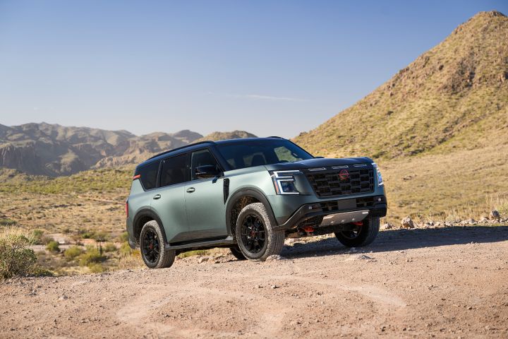 A front right 3/4 angle of a 2025 Nissan Armada PRO-4X parked at a slight incline on a rocky road.
