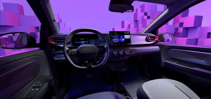 Photograph showing electric-car interior, highlighting driver cockpit, dashboard, steering wheel, infotainment screen, digital instrument display, and climate controls. Purple ambient lighting and geometric cityscape outside frame modern design, while gray fabric seats, sculpted door panels, and illuminated controls add notable details.