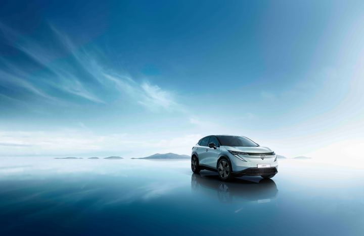 Angled right profile view of the 2027 Nissan ARIYA parked under a blue sky with a mountain range behind