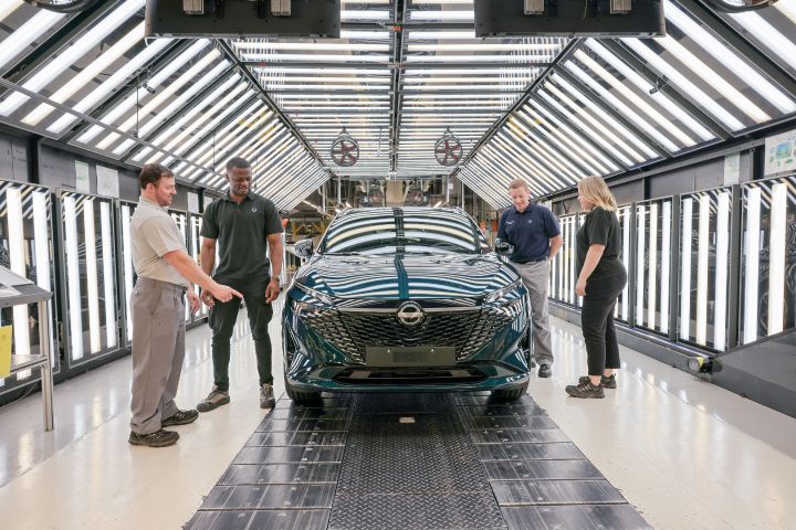 Vier Nissan Mitarbeiter stehen rund um einen dunkelgrünen Nissan Qashqai und betrachten das fertigproduzierte Auto im Nissan Werk Sunderland