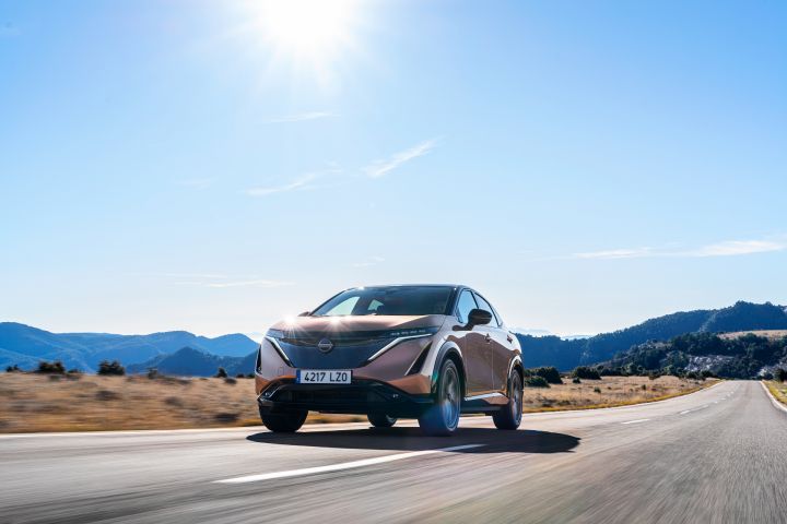 A 2021 Nissan ARIYA driving down a road.
