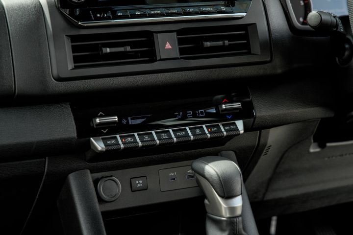 2026 Nissan Navara ST dual cab ute finished in Summit Silver with a cabin close-up of the climate controls, centre vents, switch panel and automatic gear selector.