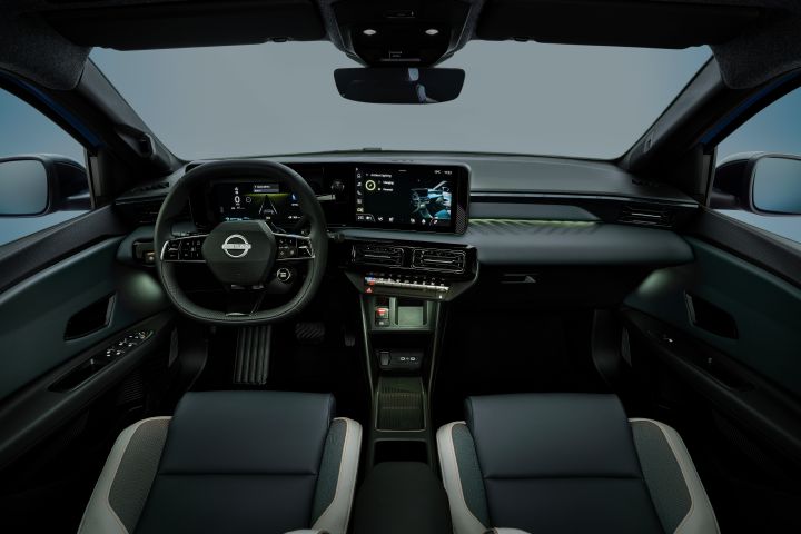 dimmed interior of Micra dashboard and cockpit from driver's POV revealing orange ambient lighting by side doors, on dashboard and below air conditioning buttons.  steering wheel, front seats and infotainment in view