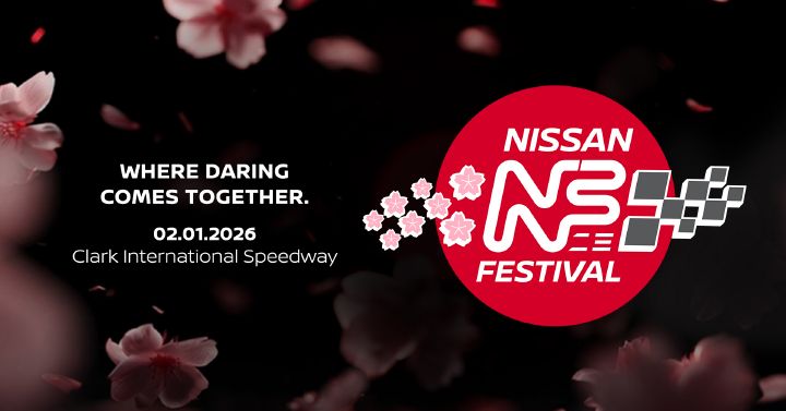 A promotional graphic for the Nissan Festival featuring a red circular logo with cherry blossom accents and a checkered flag design. The text on the left reads “WHERE DARING COMES TOGETHER. 02.01.2026, Clark International Speedway.” The background is dark with soft-focus cherry blossom petals floating across the image.