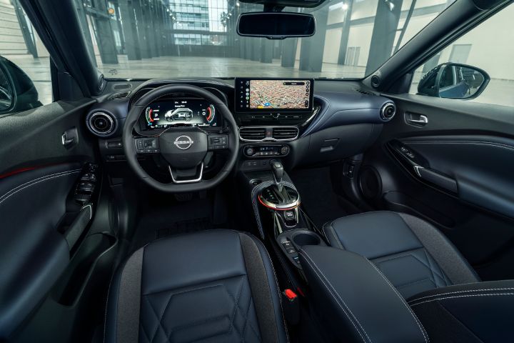Interior view of the Nissan JUKE Pulse, showing the driver-focused cockpit with digital instrument cluster, central touchscreen display, steering wheel, and black seats.