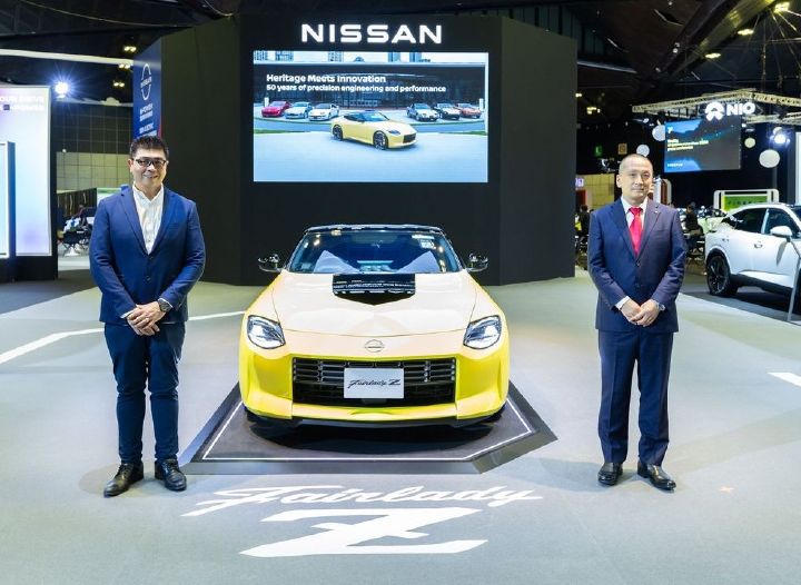 Executives from Tan Chong Motor Sales and Nissan take photo with the yellow Nissan Z displayed in front of the screen monitor.