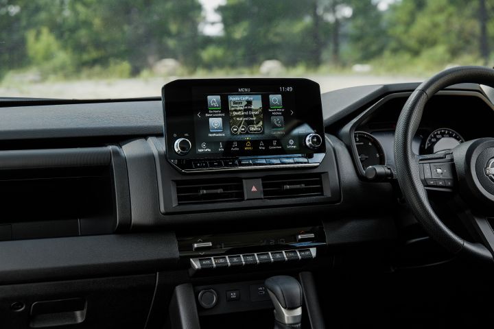 2026 Nissan Navara SL dual cab ute finished in Alpine White displaying the front dashboard, infotainment home screen, centre vents, switch panel and partial steering wheel.