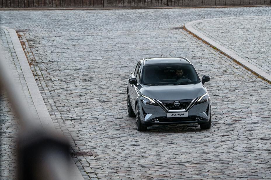 Extérieur gris Nissan QASHQAI à l’avant roulant sur une route en briques.