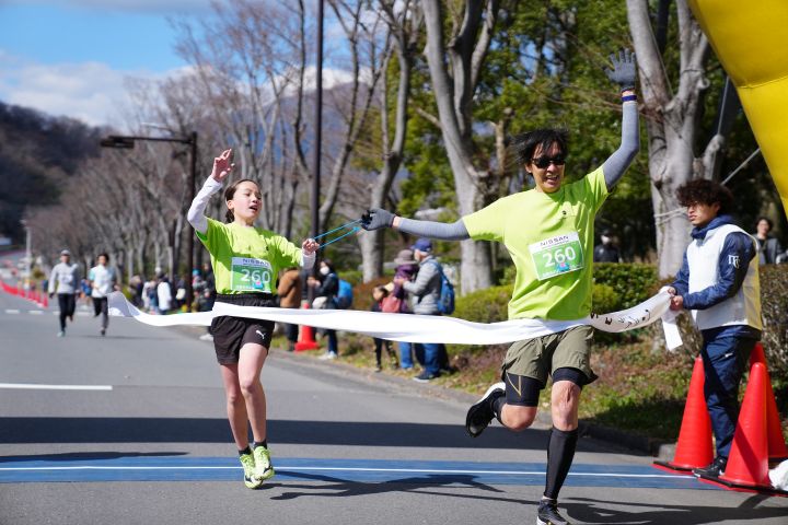 ゴールする男性ランナーと女性伴走者（ともに黄緑色のシャツ）