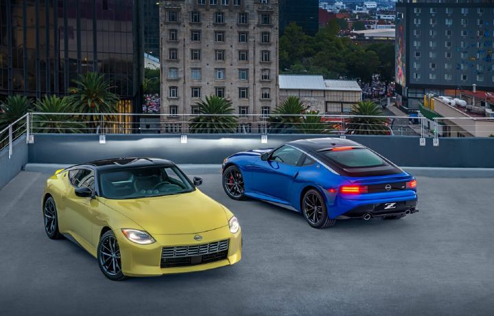 Dos Nissan Z, uno amarillo visto de frente y otro azul visto desde atrás, están estacionados uno a lado del otro