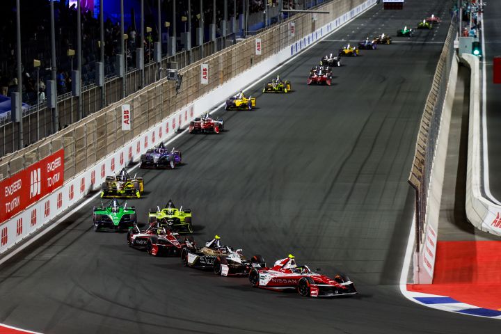 Weiter entfernte Aufnahme von Oliver Rowland, der mit dem Nissan e‑4ORCE 05 mit der Startnummer 1 den E-Prix von Dschidda anführt, während sich mehrere Autos auf der Start-Ziel-Geraden hinter ihm aneinander reihen